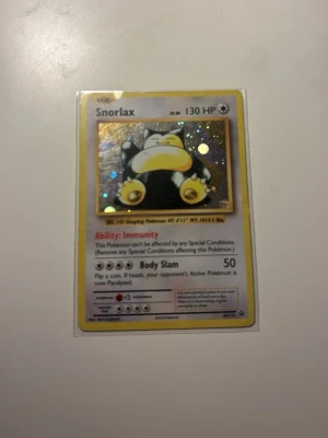 Snorlax holografiskt Pokémonkort - Säljer ett holografiskt Snorlax Pokémonkort med 130 HP. Kortet har gul ram, glittrande effekt och klassisk Pokémon-design. Perfekt för samlare eller dig som vill boosta din kortlek. Materialet är hård papp med plastskydd.