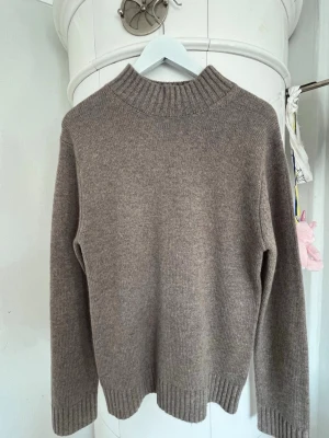 Beige stickad turtleneck - Mysig beige stickad tröja från Sandö med hög ribbad krage och långa ärmar. Tröjan har en enkel, rak passform och ribbade muddar vid ärmslut och nederkant. Perfekt för lager på lager och en clean look. Storlek s. Kolla även mina andra annonser så kan vi lösa ett paketpris