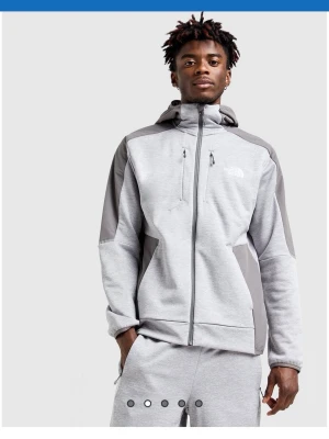 Grå hoodie från The North Face - Säljer en snygg grå hoodie från The North Face med dragkedja framtill och kontrasterande mörkgrå paneler på axlar och sidor. Hoodien har två stora fickor, bröstficka med dragkedja och justerbar huva. Perfekt för chill eller streetwear.