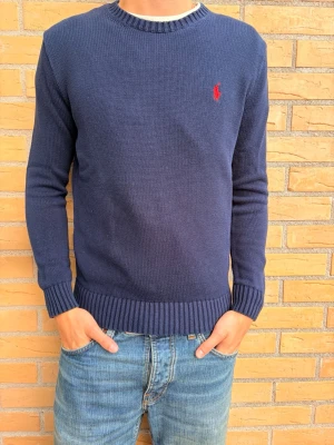 Mörkblå stickad tröja Polo Ralph Lauren - Tjena! Säljer nu en mörkblå stickad tröja från Polo Ralph Lauren med rund halsringning och ribbade muddar. Tröjan har en liten röd logga broderad på bröstet och är långärmad. Tröjan är köpt i USA och är 100% äkta. Tveka inte att höra av dig, mvh Leo!
