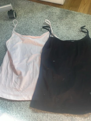 2-pack linnen från Gina Tricot - Säljer två linnen från Gina Tricot i storlek 158/164. Ett är ljusrosa och det andra är svart, båda med smala axelband och enkel, klassisk design. Perfekta att matcha till olika outfits och superbekväma att bära.