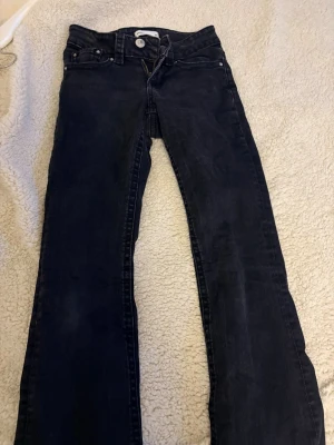 Svarta bootcut jeans - Säljer ett par svarta bootcut jeans med låg midja och klassisk femficksmodell. Jeansen har en lätt utsvängd passform nedtill och stängs med dragkedja och knapp. Perfekta för en avslappnad och trendig look.