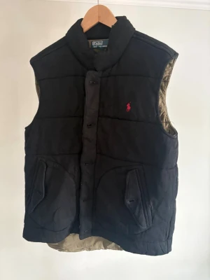  Polo Ralph Lauren Väst - Svart dunväst från Polo Ralph Lauren. Mycket fint skick. Köpt för 2600kr säljer nu pga flytt. Svår och få tag i!!