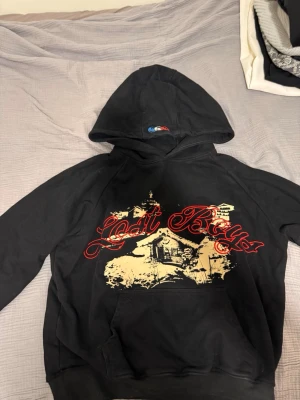 Lost boys hoodie - Cool svart hoodie med stor huva och tryck i rött och beige som föreställer texten 'Lost Boys' och en stuga i snölandskap. Hoodien har känguruficka framtill och avslappnad passform. Perfekt för dig som gillar streetwear och unika prints. Säljer den då  den ej passade mig passar mer för M i storlek men är i storlek L, Har aldrig använts i min ägo bara testat. Tveka inte på att höra av er:)