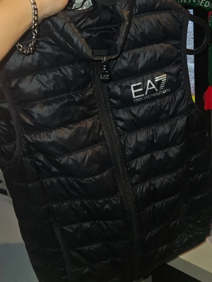 Äkta Emporio Armani väst - Äkta svart Emporio Armani väst i storlek XS och den är i bra skick förutom ett litet hål på baksidan men bortsätt från de så är det inga mer. OPS! Jag kan bara skicka med PostNord.