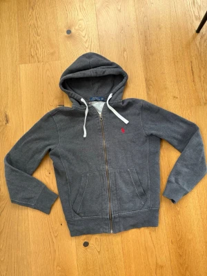 Mörkgrå Ralph lauren zip up hoodie - Säljer en Ralph lauren zip up hoodie nu när den är för liten, är en gammal modell  och är lite skrynklig på bilden men jag stryker den innan den säljs 