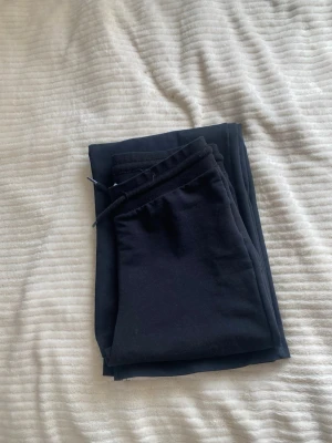 Svarta mjukisbyxor med dragsko - Säljer ett par svarta mjukisbyxor med dragsko i midjan. Byxorna har en enkel och clean design, raka ben och är gjorda i mjukt och bekvämt material, perfekt för chill dagar hemma eller när du vill vara extra comfy.