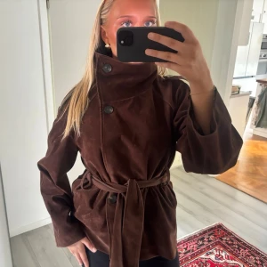 Brun suede jacka - Säljer min superfina bruna trenchcoat i mocka från Gina Tricot. Går att knäppa upp i kragen och har ett band i midjan. Den är i storlek S och jag är 165 cm🤎