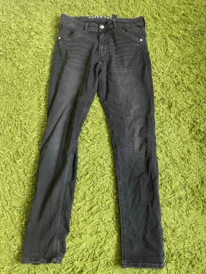 Svarta skinny jeans från Superdry - Snygga svarta skinny jeans från Superdry med klassisk femficksdesign och diskreta sömmar. Jeansen har smal passform och stretchigt material som sitter tajt längs benen. Perfekta för en trendig och avslappnad stil.