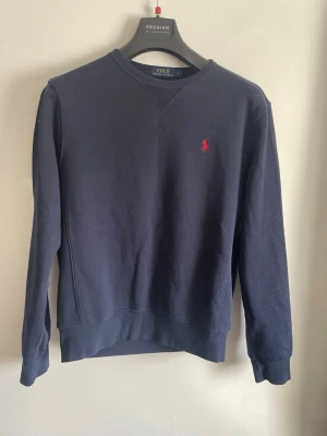 Ralph Lauren tröja, strl S - En riktigt fin tröja från Polo Ralph Lauren i marinblå färg. Mycket bra skick förutom att den är lite små nopprig nedtill. Inget som märks vid användning enligt mig.  Storlek: S Självklart äkta och skickas inom 24h efter köp!  Hör av er vid funderingar.