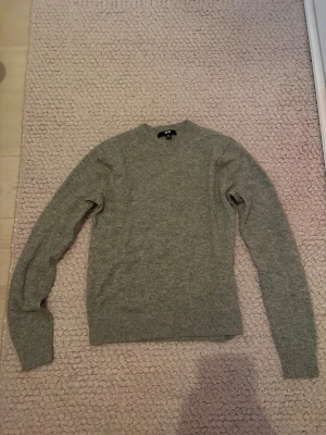Grå cashmirtröja tröja från Uniqlo - Säljer en enkel och stilren grå stickad tröja från Uniqlo i storlek XXS. Tröjan har rund halsringning, långa ärmar och är 100% cashmir. Perfekt basplagg till garderoben. Säljer även en likadan i mörkblå