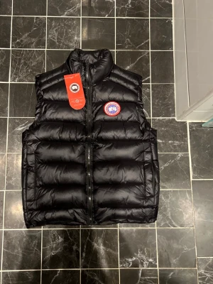 Canada Goose Väst - En mycket fin aldrig använd Canada Goose väst. Plagget har inga defekter därmed i nyskick, säljs pga ingen användning och sitter fint i storlek:)                                                      Priset kan diskuteras!