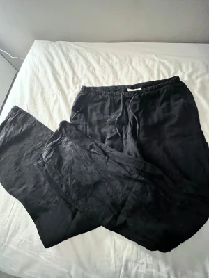 Svarta linnebyxor från Gina Tricot - Säljer ett par svarta linnebyxor från Gina Tricot med avslappnad passform och resår i midjan. I storlek 170 men passar även säkert 158/164💞.