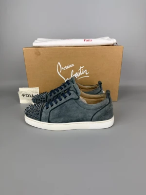 Christian Louboutin Louis Junior Spikes Sneaker Washed Blue | 40 - Sparsamt använd sneaker i mycket gott skick. Färg: Washed Blue. Box, dustbag och kvitto medföljer.