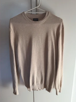 Beige stickad tröja från Sinsay Men - Snygg beige stickad tröja från Sinsay Men i 100% bomull. Tröjan har rund halsringning, långa ärmar och ribbade muddar vid ärmslut och nederkant. Perfekt för lager på lager och enkel att matcha med olika outfits.