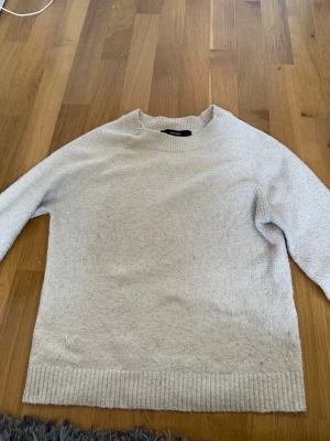Ljusgrå stickad tröja - En enkel och stilren ljusgrå stickad tröja med rund halsringning och ribbade muddar vid ärmslut och nederkant. Perfekt för lager på lager och passar till det mesta i garderoben. Mjuk och skön känsla.
