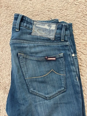 Jacob Cohën jeans med slitningar - Säljer ett par blå jeans i smal passform, st 30/30, med snygga slitningar på benen. Tydliga tecken på användning men håller fortfarande schysst standard. Perfekta för dig som gillar en trendig och casual stil. Hör gärna av dig vid ev frågor!