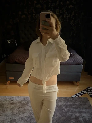 Vit knytblus - Säljer en vit skjorta med knyt framtill. Skjortan har långa ärmar, två stora bröstfickor och knappar hela vägen. Perfekt för dig som gillar en avslappnad och trendig look.