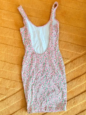 Blommig kort klänning med smala axelband - Strl.Small - Endast använd vid ett tillfälle!Söt kort klänning från American Apparel med smala axelband och blommigt mönster i rosa, grönt och vitt. Klänningen har en figurnära passform och är perfekt för varma dagar. Tillverkad i mjukt bomullstyg som känns bekvämt mot huden.