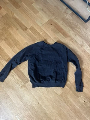 Svart sweatshirt från 157 - En enkel och stilren svart sweatshirt från 157 med rund halsringning och ribbade muddar vid ärmslut och nederkant. Perfekt för en avslappnad look och lätt att matcha med jeans eller mjukisbyxor.