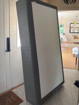Grå säng, 105x200cm  - En säng från ikea, knappt andvänd. Hemkörning av sängen kan ske om du bor I Stockholm. Du får med fyra svarta metall ben från Mio(sprillans nya och 19cm höga). Bäddmadrass ingår! Perfekt för dig som vill ha en enkel och stilren säng till sovrummet eller gästrummet. Bäddmadrass ingår
