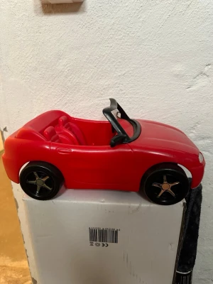Röd leksaksbil cabriolet - Säljer en röd leksaksbil i plast med cabriolet-design. Bilen har svarta detaljer, två säten och sportiga svarta hjul med silverfärgade ekrar. Perfekt för dig som gillar bilar och vill ha något snyggt till samlingen eller leken.