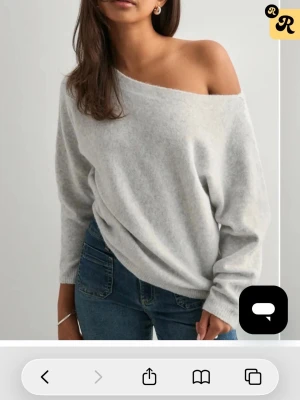 Ljusgrå off shoulder stickad tröja - Mysig ljusgrå stickad tröja med off shoulder-design och avslappnad passform. Tröjan har långa ärmar och mjukt material som ger en chill vibe. Perfekt att styla med jeans för en enkel men snygg look.