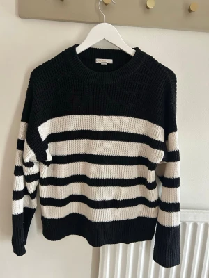 Svartvit randig stickad tröja - Säljer en oversized stickad tröja med breda svarta och vita ränder. Tröjan har rund halsringning, långa ärmar och är gjord i ett tjockare, mjukt material som känns riktigt cozy. Perfekt för lager på lager och chill dagar.