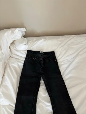 Svarta raka jeans  - Säljer ett par svarta jeans med rak passform och klassisk femficksmodell med bälteshällor och knappgylf. Jeansen har en stilren look och passar perfekt till en avslappnad vardagsstil.