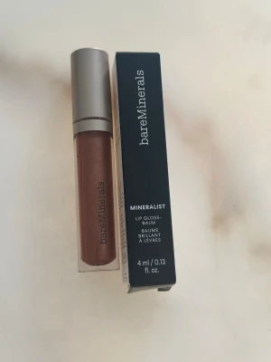 bareMinerals Mineralist Lipgloss Warmth - Mineralist Lip Gloss-Balm från bareMinerals i färgen Warmth. Ett läppglans med skimrande, varm brunrosa ton och mjuk applikator. Kommer i en stilren tub med silverlock och tillhörande förpackning. Innehåller 4 ml. Oöppnad!