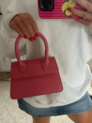 Rosa handväska - Söt liten handväska i starkt rosa färg. Perfekt om man vill göra sin outfit lite roligare💕💕