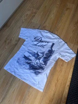 Leon marcel T-Shirt – Vit | Strl S |  - Leon marcel  t-shirt i vit med blå grafik på ryggen — clean design som passar perfekt för sommaren
