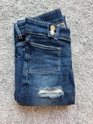 Blå flare jeans från Gina tricot 14+ - Ett par blåa flare jeans från Ginatricot med hål. Säljer dessa pågrund av att de har blivit försmå. 