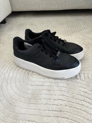 Nike air force  - Svarta Nike airforce med vit tjockare sula. Det finns några svarta märken från användning på sulan. 