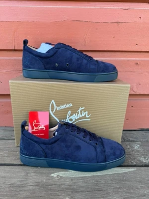 Mörkblå sneakers från Christian Louboutin - Snygga mörkblå sneakers i mocka från Christian Louboutin. Skorna har en stilren design med matchande mörkblå snörning och diskreta detaljer. Yttersulan är också mörkblå och insidan har guldfärgad logga. Perfekta för dig som gillar exklusiva och trendiga skor.skorna är ej autentiska. Perfekt nu för skolstarten!