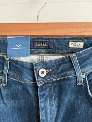 Salsa Jeans | Push Up Wonder | Premium Denim - Säljer Salsas populära Push Up Wonder-modell som är designad för att ge en snygg kurvig passform. Tillverkade av mjuk och bekväm stretchdenim av hög kvalitet som formar och framhäver silhuetten. En tidlös favorit som passar till alla tillfällen. Helt nya och oanvända med originaltagg kvar. 