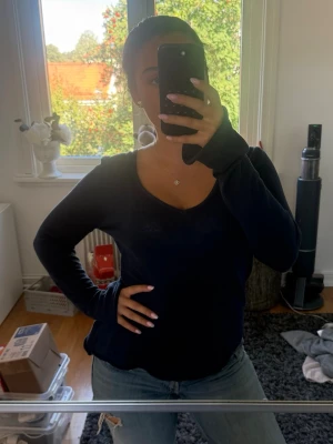 Mörkblå v-ringad långärmad tröja - En enkel och stilren mörkblå långärmad tröja med v-ringning. Tröjan har en avslappnad passform och är tillverkad i ett mjukt, tunt material som passar perfekt till jeans eller kjol. Perfekt basplagg för din garderob.