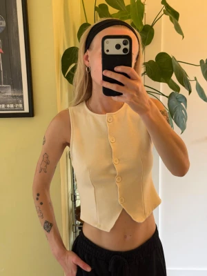 Crémefärgad väst topp från Gina Tricot  - Mjuk väst i en crémefärg från Gina Tricot. Aldrig använd endast tvättad och hängd i garderoben.