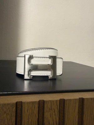 Vitt bälte  - Snyggt vitt bälte . Perfekt accessoar för att lyfta vilken outfit som helst. Skärpet har tydliga sömmar längs kanterna för en clean look.