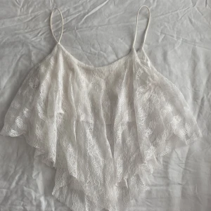 Vit spetslinne - Säljer ett vackert vitt spetslinne med tunna axelband och volangdetaljer. Perfekt för en sommaren🤍