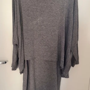 Grå klänning från Made in Italy - Säljer en stilren grå klänning från Made in Italy. Klänningen har en lös passform med långa ärmar och är tillverkad i ett mjukt material. Perfekt för en avslappnad look. Passar S-M