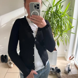 Svart ribbad kofta - En fin svart kofta med fina snygga knappar dock den högsta knappen saknas men inget man märker  