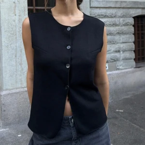 Svart väst med knappar - Snygg svart väst från Nelly med knappar framtill. Aldrig använd!