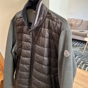 Grå quiltad jacka från Moncler - Säljer en stilren grå quiltad jacka från Moncler med dragkedja och långa ärmar. Jackan är i bra/okej skick 7/10 ungefär. Den är köpt från vongreven closet för ett halv år sen ungefär men är knappt använd pga att den är för liten för mig. Köpt för 3,500.                                                    Storlek M men är liten i storleken. 