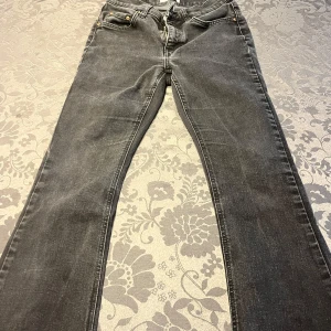Grå jeans med fransade kanter - Snygga grå jeans med en klassisk design och fransade kanter vid bensluten. De är för korta ben men är perfekta för en avslappnad stil. Jeansen har fickor fram och bak samt en dragkedja och knapp i midjan. Köpta för 500kr.