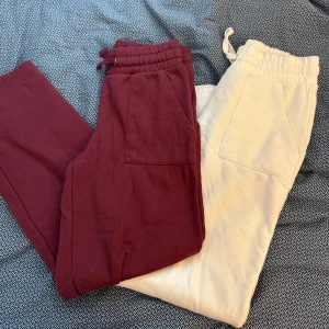 Vinröda och vita mjukisbyxor - Två par mjukisbyxor i vinrött och vitt. Byxorna har elastisk midja med snörning och praktiska fickor. Perfekta för en avslappnad stil. 110 för bägge!