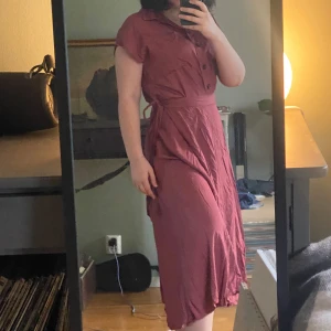 Vinröd set, topp med knappar och kjol - Säljer en vinröda set, en topp med knappar framtill och kjol som är knytband i midjan. Toppen har korta ärmar och en klassisk krage. Perfekt för en stilren och bekväm look. Lite skrynklig men går fort att lösa med ett strykjärn🥰 går även att köpa delar separat 