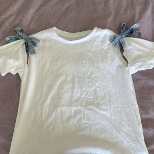 Vit t-shirt med denimrosetter - vit t-shirt med unika denimrosetter på axlarna.💙💙💙