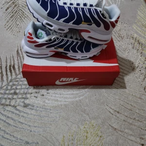 Nike sneakers i blått och vitt - Snygga Nike sneakers i blått och vitt med unika detaljer och texten 'ICI C'EST PARIS' på plösen. Skorna har en modern design med vita snören och en bekväm sula. Perfekta för dig som vill ha stil och komfort i ett.