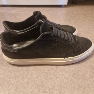 Axel Arigato  - Snygga svarta sneakers från Axel Arigato. Tappat en liten del på höger foten men annars jätte fina. Inte slitna i skon och är riktigt sköna. Rekommenderar kommer inte ångra er. 